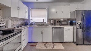 Una cocina moderna con armarios blancos, un refrigerador de acero inoxidable, un microondas y una estufa.