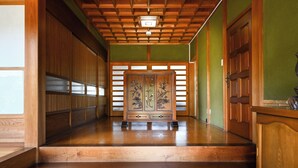Un couloir intérieur au rev êtement de bois, doté d’un plancher poli, de portes coulissantes traditionnelles et d’un plafond avec des poutres en bois.