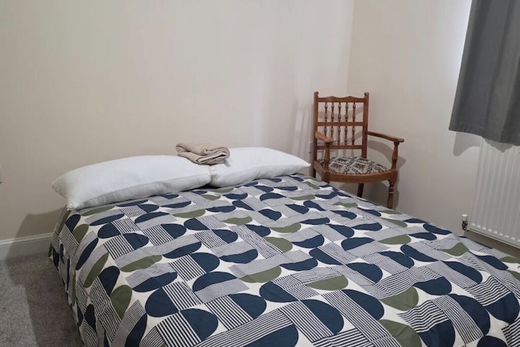 A bedroom with a bed, a chair, and a window.