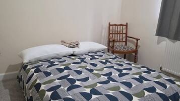 A bedroom with a bed, a chair, and a window.