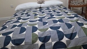 Ein Bett mit einem gemusterten Überwurf, einem weißen Kopfkissen und einem gefalteten Handtuch.