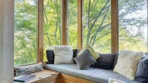 Un coin salon confortable avec un banc rembourré, des coussins et une petite table sur laquelle se trouvent un livre et une tasse.