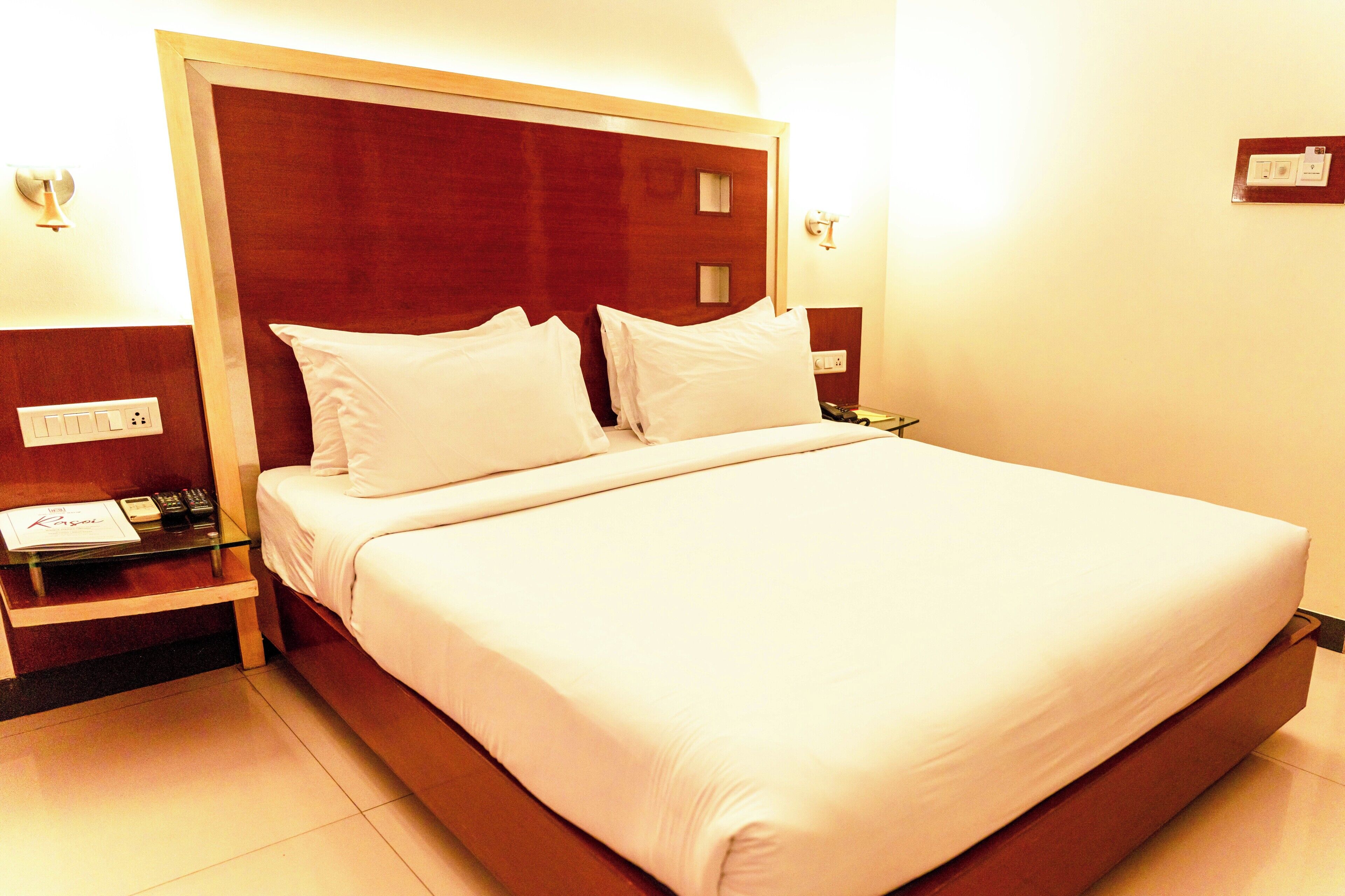 A neatly made bed with white linens in a hotel room.