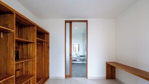 Een hal met een houten boekenkast, een bank en een deur naar een badkamer met een spiegel en wastafel.