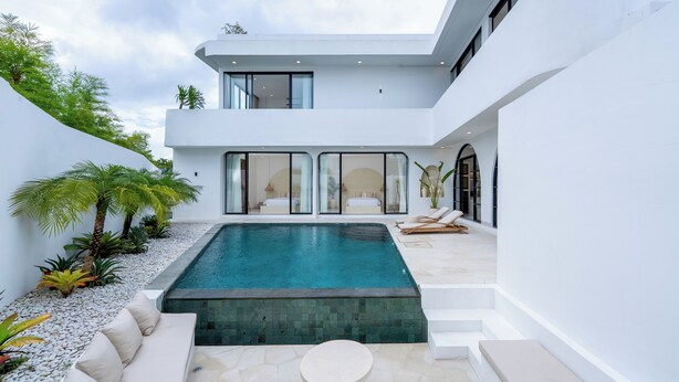 Een modern huis met een zwembad, terras en een balkon.