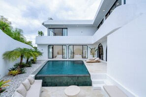Een modern huis met een zwembad, terras en een balkon.