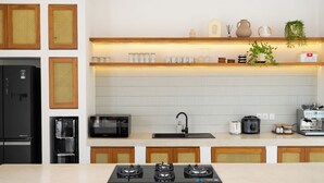 Een moderne keuken met een gasfornuis, een magnetron, een koffiezetapparaat en een waterdispenser.