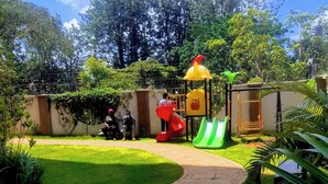Un sendero pavimentado que conduce a un parque infantil con toboganes y una estructura para escalar.