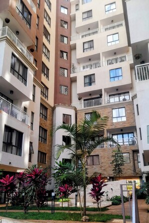Un edificio residenziale a più piani con balconi, un cortile con piante e un muro in pietra.