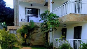 Un edificio de varios pisos con balcones, fachada de piedra y un césped cuidado con un camino de piedra.