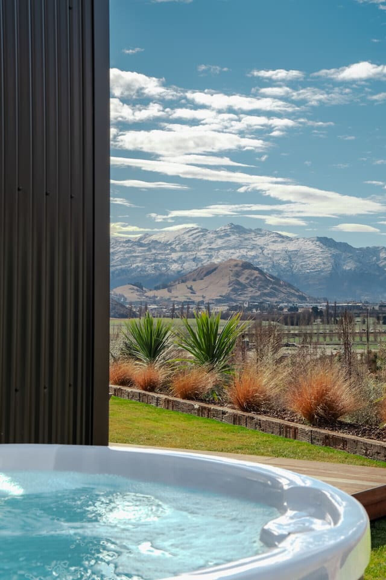A hot tub with a view of a mountainous landscape and a city in the distance.
