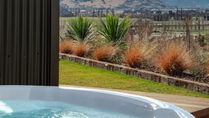 A hot tub with a view of a mountainous landscape and a city in the distance. - Private Spa with Remarkables & Coronet Views (Jacks Point)