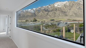 A room with a large window offering a view of a mountainous landscape and a bridge. - Private Spa with Remarkables & Coronet Views (Jacks Point)