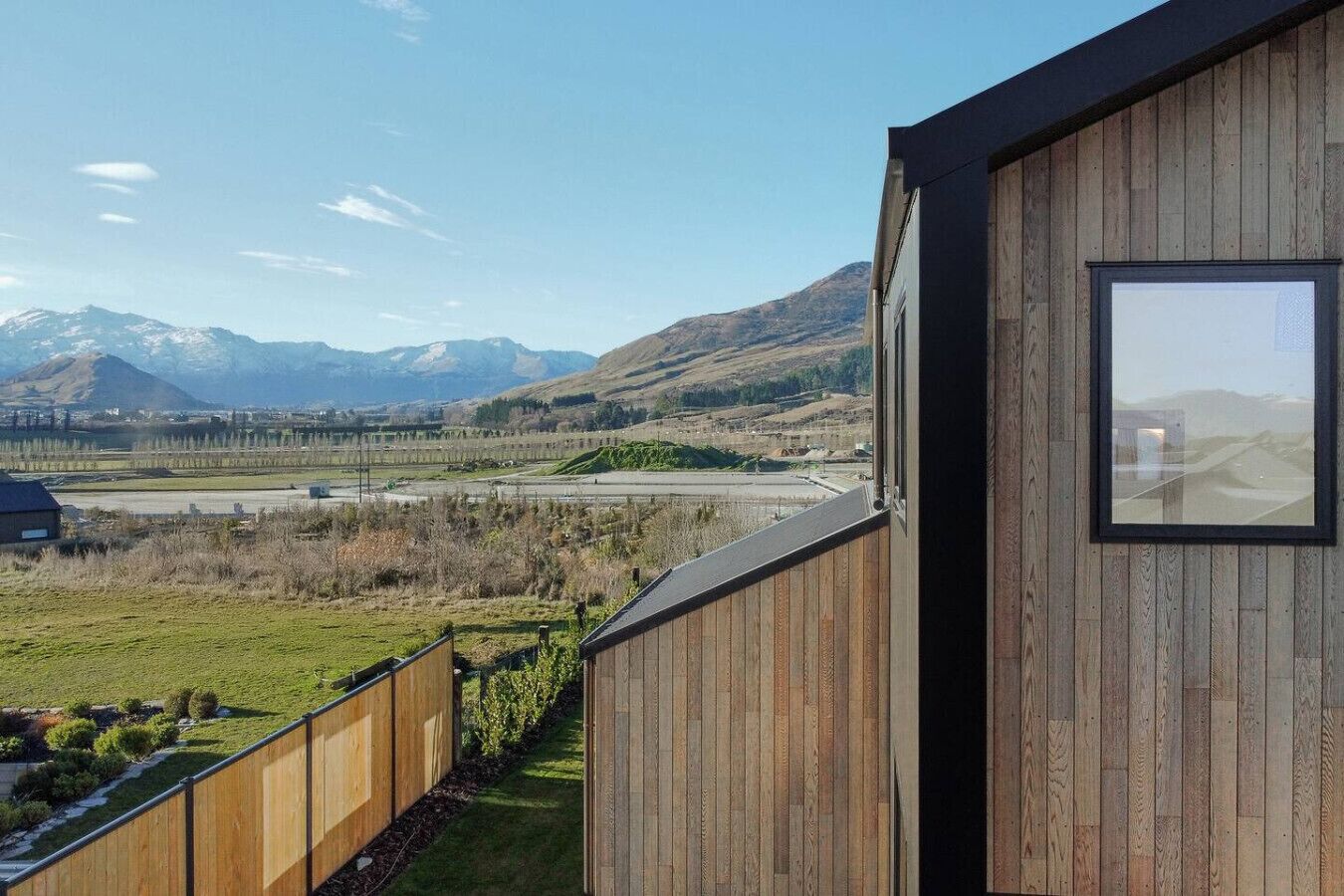 A wooden building with a large window overlooking a mountainous landscape and a highway.