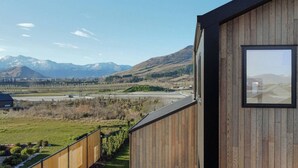 A wooden building with a large window overlooking a mountainous landscape and a highway. - Private Spa with Remarkables & Coronet Views (Jacks Point)