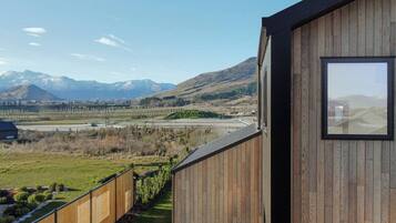 A wooden building with a large window overlooking a mountainous landscape and a highway.