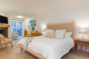 Una camera da letto con un letto, un divano, una televisione e un camino.