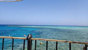 A clear view of the ocean from a balcony with a wooden railing.