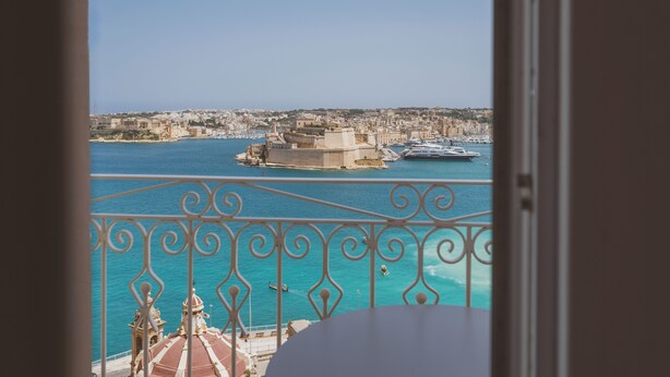 Ein Balkon mit Blick auf eine Küstenstadt, ein großes Gebäude und eine Yacht im Wasser.