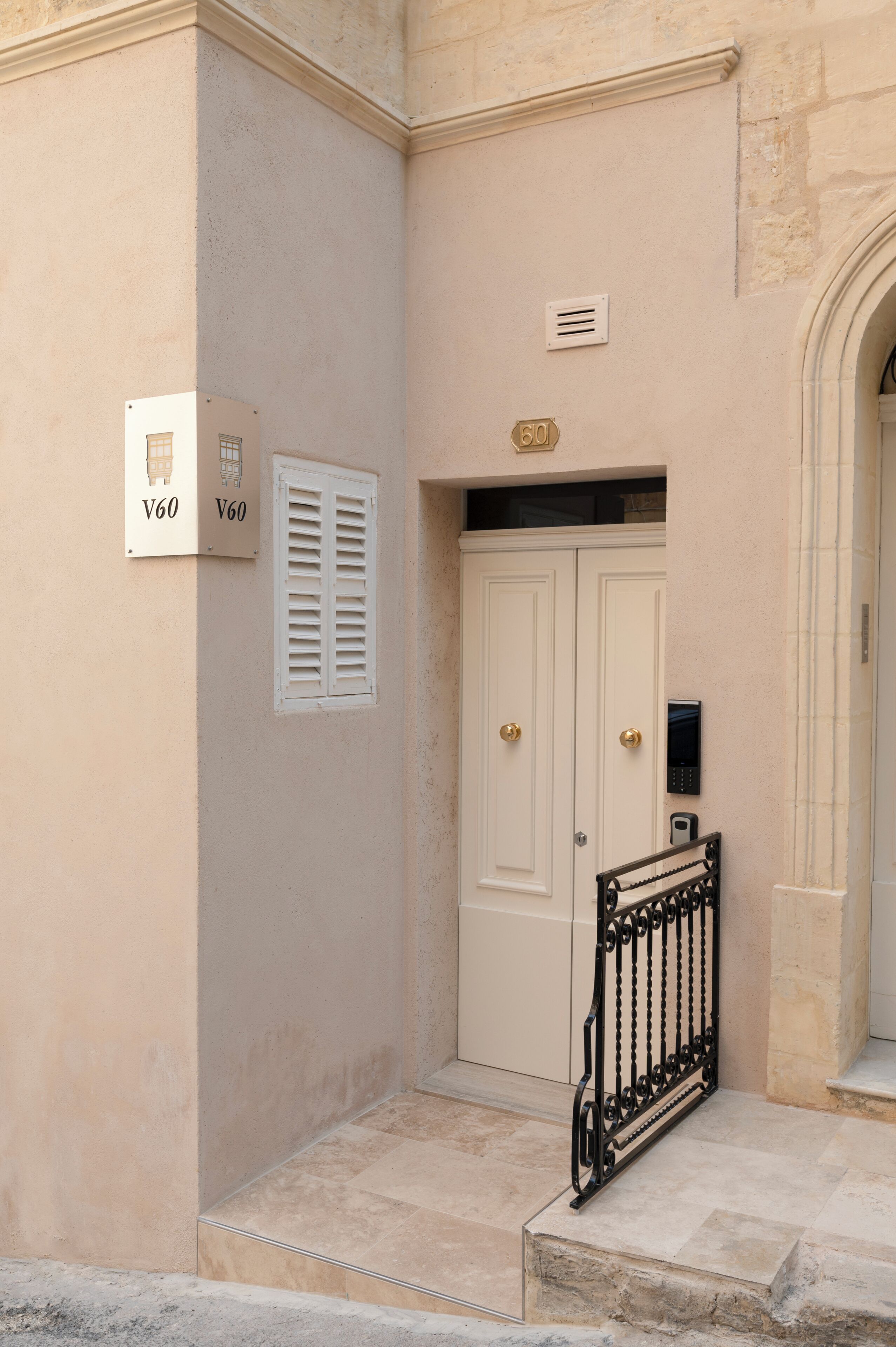 Fachada de un edificio con puerta doble, buzón y portón de seguridad.