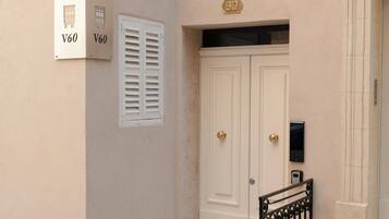Fachada de un edificio con puerta doble, buzón y portón de seguridad.