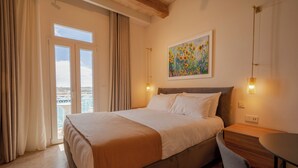 Ein Hotelzimmer mit Bett, Schreibtisch, Stuhl, einem Gemälde und Blick durch das Fenster.