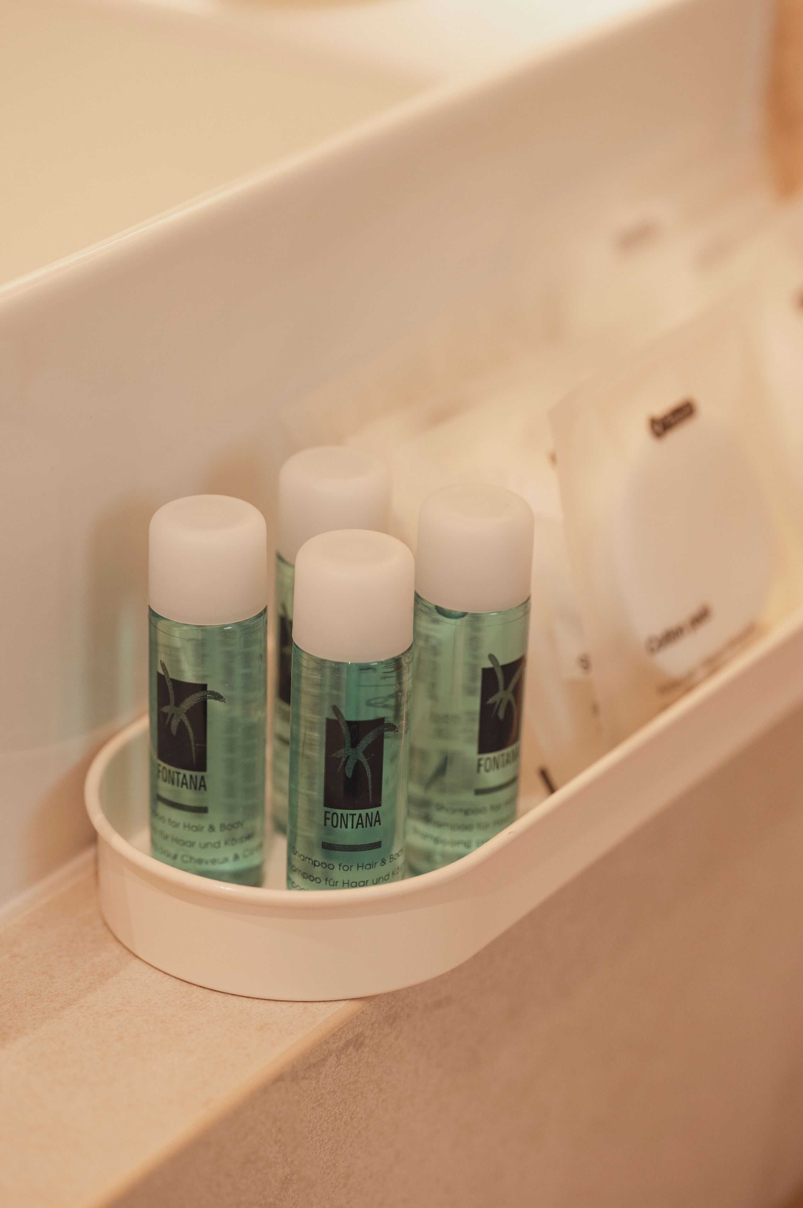A bathroom shelf with three bottles of Fontana hair and body shampoo.