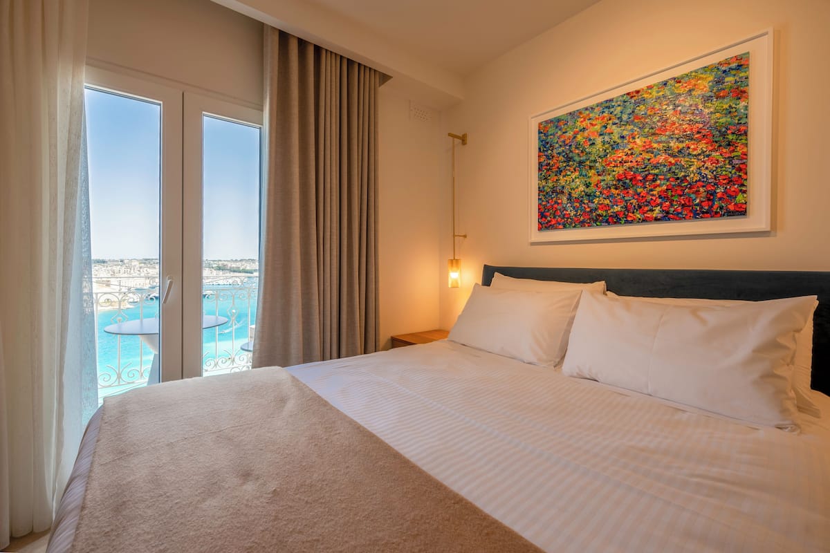 Habitación de hotel con cama, un cuadro, vistas a una piscina y un balcón.