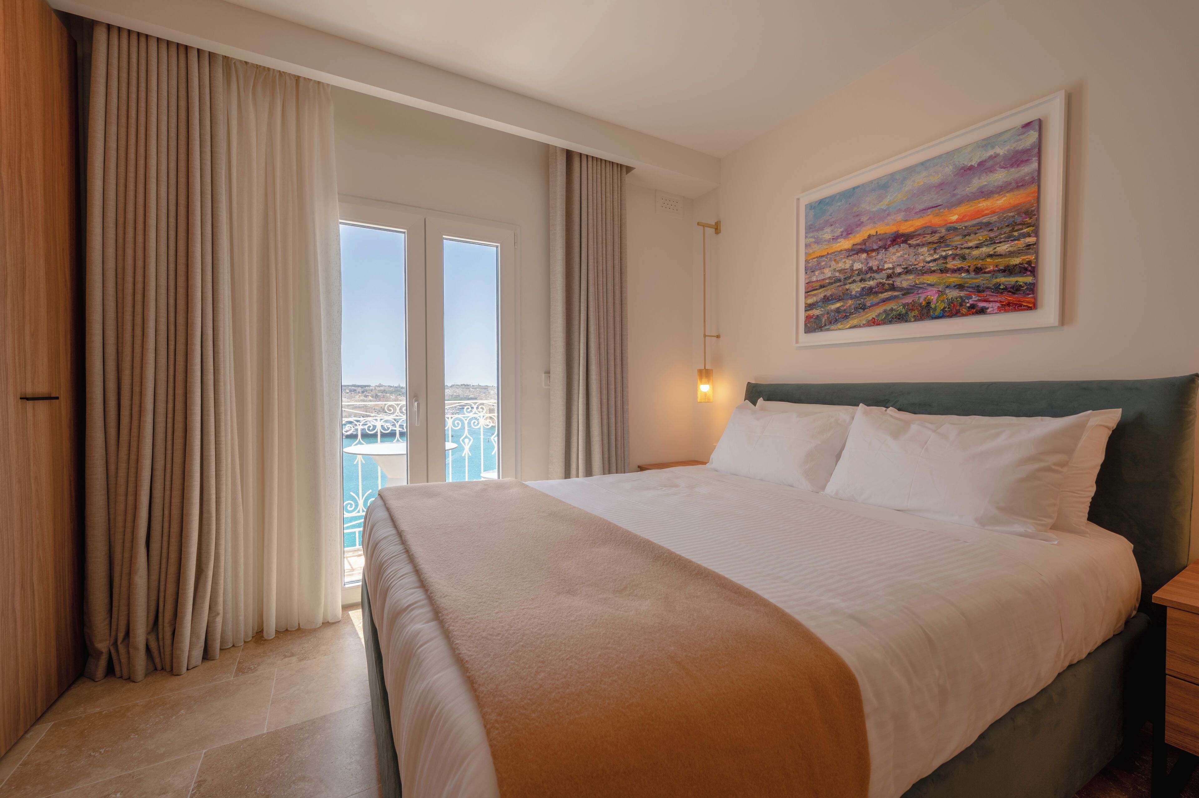 Habitación de hotel con una cama grande, vistas de la ciudad por la ventana y un cuadro en la pared.