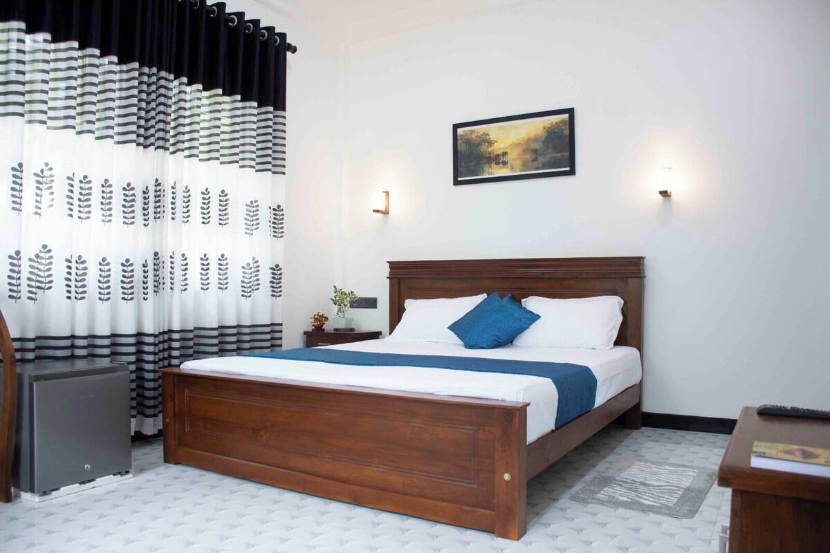 A neatly arranged bedroom with a wooden bed, a nightstand, a lamp, and a framed picture on the wall.