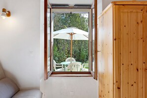 A room with a window, a white chair, and a wooden cabinet.