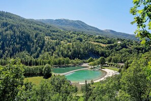 A mountainous landscape with a lake, surrounded by dense forests and a few buildings.