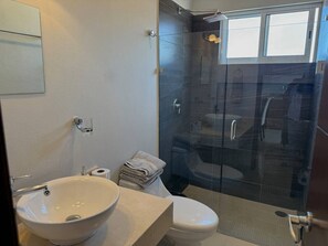 Une salle de bain avec une douche à parois de verre, un lavabo blanc et des toilettes.