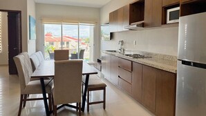 A modern kitchen with wooden cabinets, stainless steel appliances, and a dining area with a table and chairs.