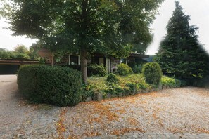 A stone building with a gravel driveway, surrounded by well-maintained hedges and trees. - Apartment 'In the Green' with Private Terrace and Wi-Fi (Mammelzen)