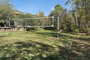A volleyball net set up in a grassy area with trees in the background.