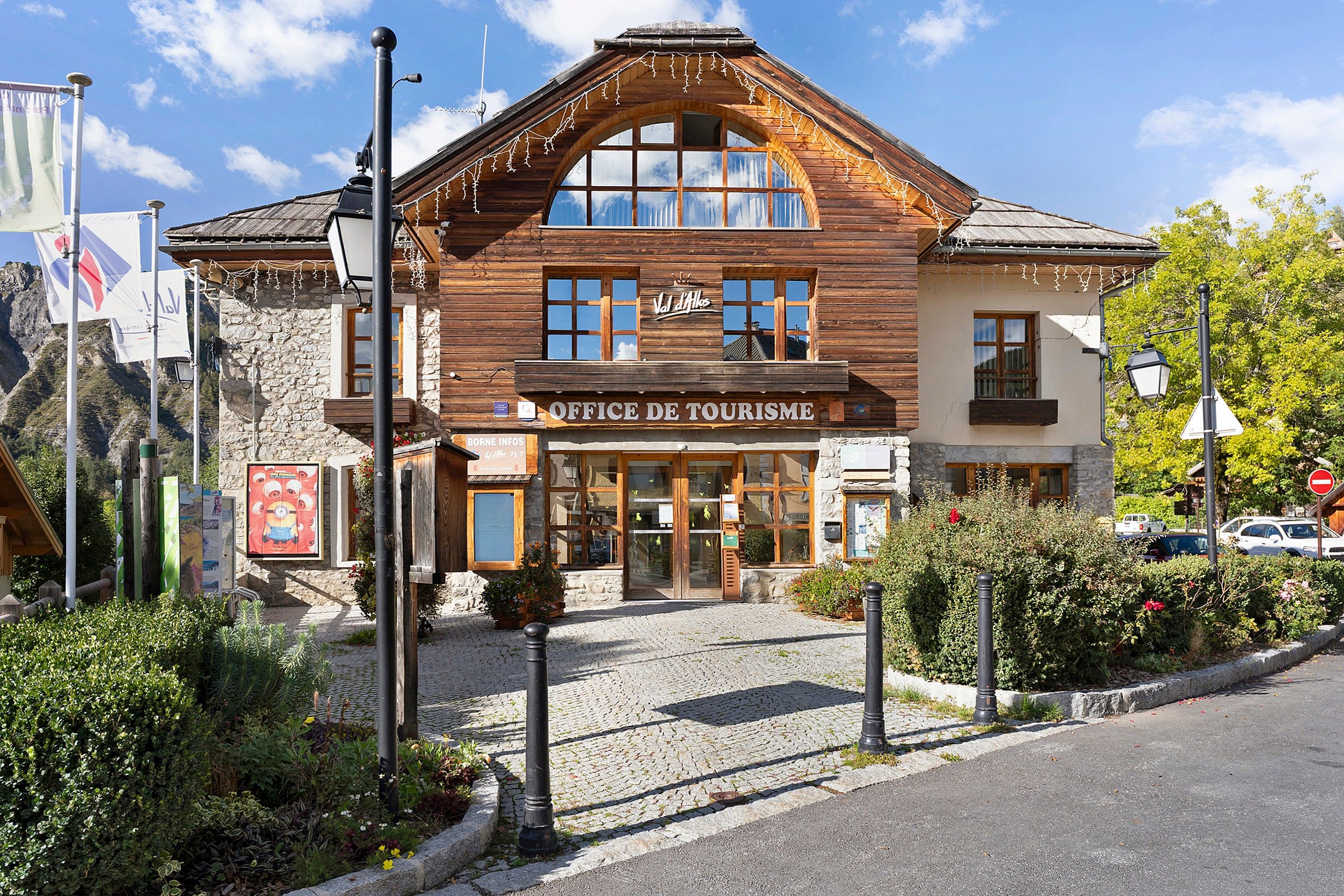 Un edificio de madera con un letrero que dice 'Office de Tourisme' y fachada de piedra.