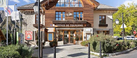 A wooden building with a sign reading 'Office de Tourisme' and a stone facade.