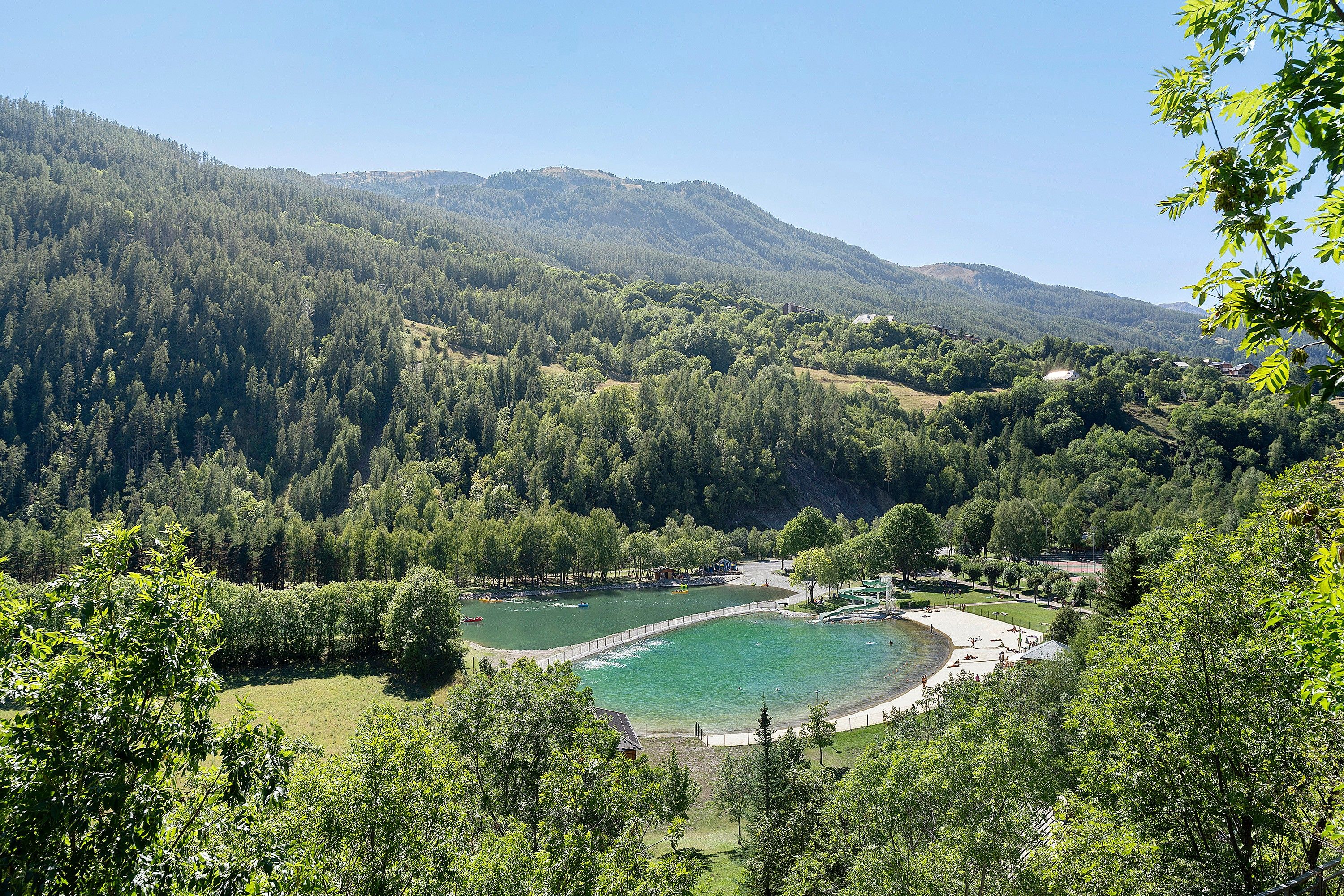 Un lago rodeado de colinas boscosas, con un pequeño muelle y un bote.