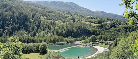 A lake surrounded by forested hills, with a small dock and a boat.