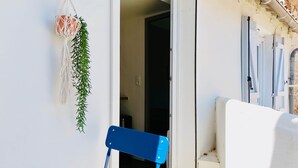 A room with a white wall, a blue chair, and a macrame hanging decoration. - Juni - Air-conditioned & Balcony (Brignoles)