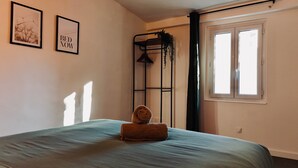 A bedroom with a bed, a wall-mounted shelf with a plant, and a window with curtains. - Juni - Air-conditioned & Balcony (Brignoles)