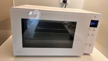 A white LG microwave oven with a digital display, placed on a speckled countertop.