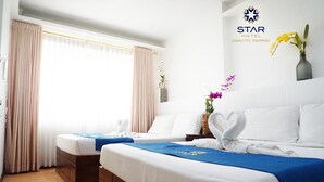 A hotel room with two beds, a large window with curtains, a vase with flowers, and a Star Hotel logo. - Star Hotel Davao (Davao)
