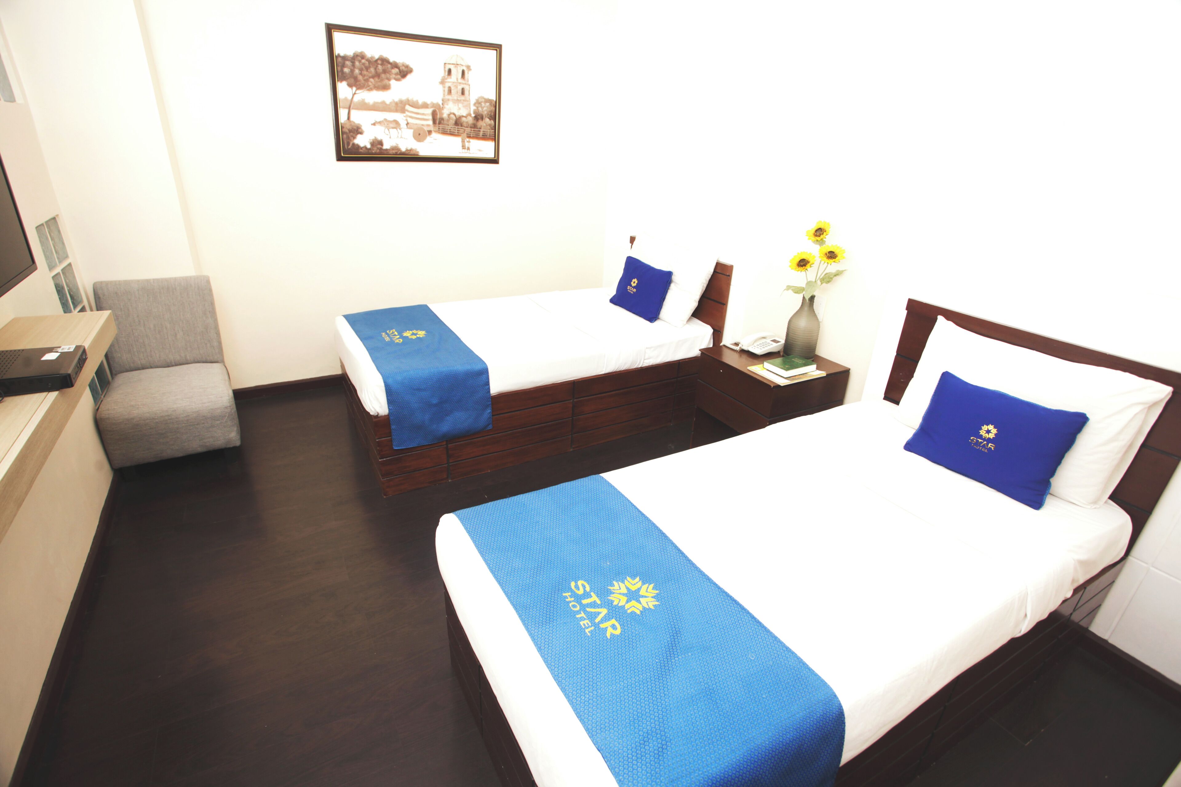 A hotel room with two beds, a desk, and a chair.