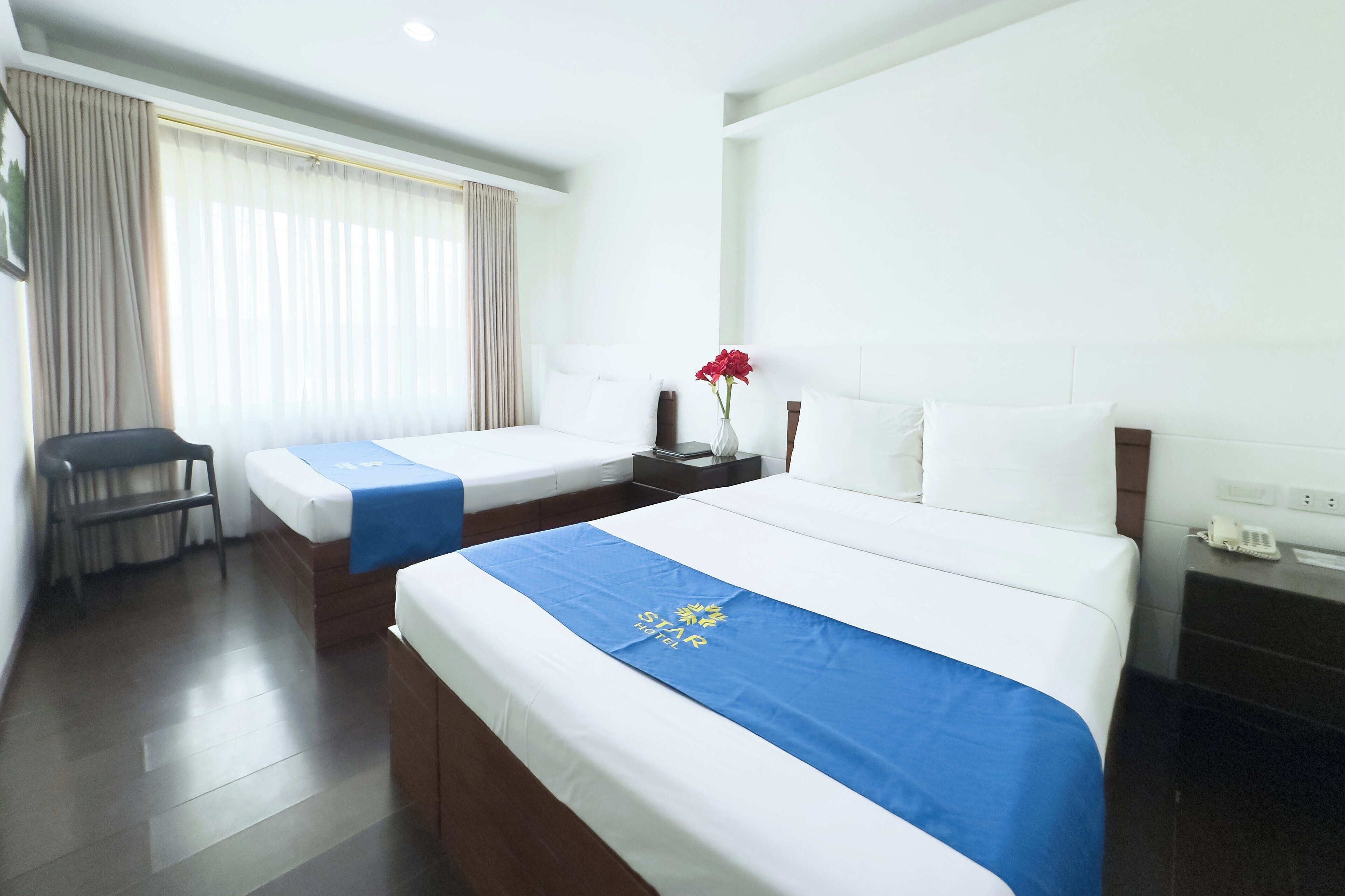 A hotel room with two beds, a desk, and a chair.