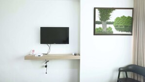 A hotel room with a mounted TV, a wooden shelf with a sign, and a framed picture of a lake. - Star Hotel Davao (Davao)