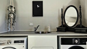 A compact laundry area with a washing machine, dryer, and a small sink with a mirror.