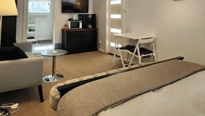 A hotel room with a bed, a desk, a chair, a television, and a window.