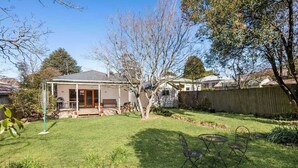 A backyard with a covered patio, a lawn, and a wooden fence.